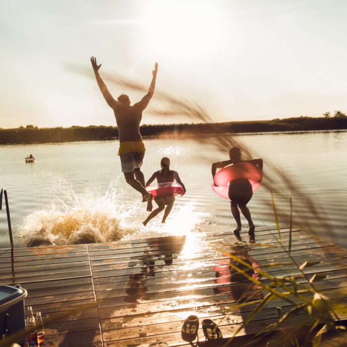 Friends having fun enjoying a summer day swimming and jumping at